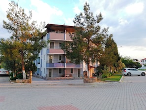 Ein mehrstöckiges Hotel mit Balkonen, einer Schautafel und einem gepflasterten Eingangsbereich.