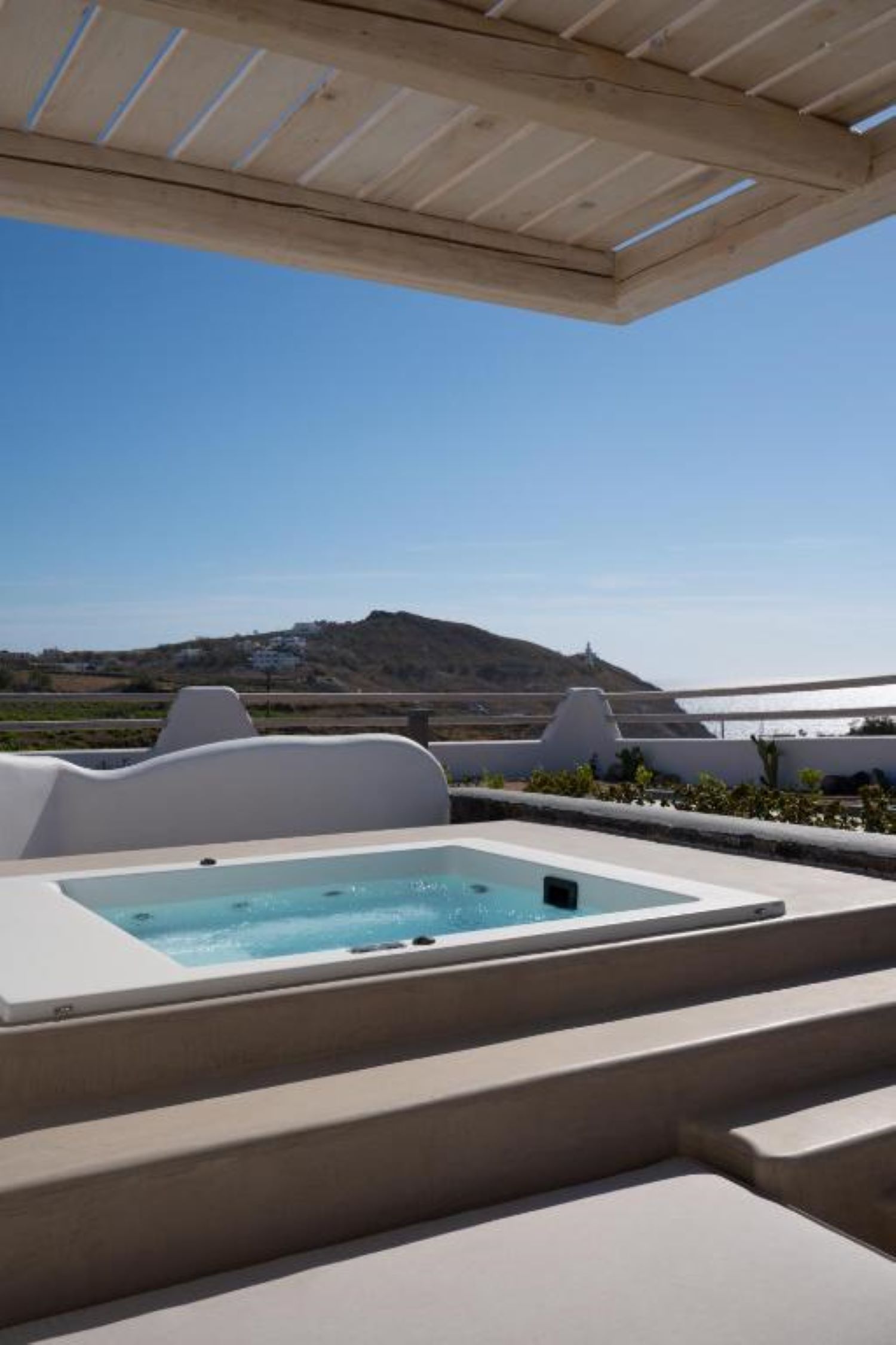 Um terraço no telhado com hidromassagem, área de estar externa e vista para a costa.