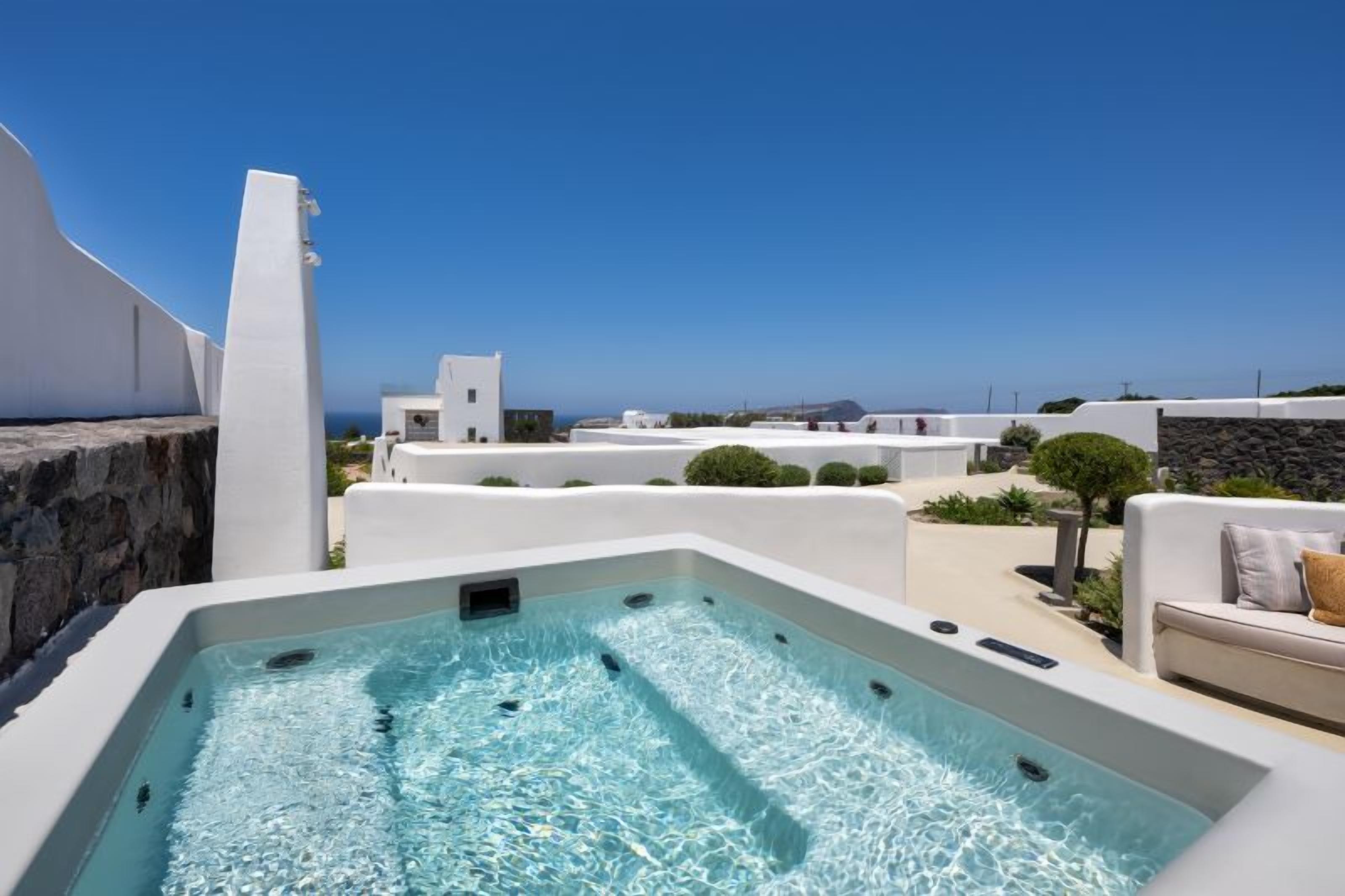 A rooftop pool with clear blue water, white buildings, and a view of the sea.