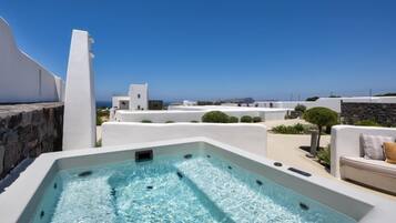 A rooftop pool with clear blue water, white buildings, and a view of the sea.