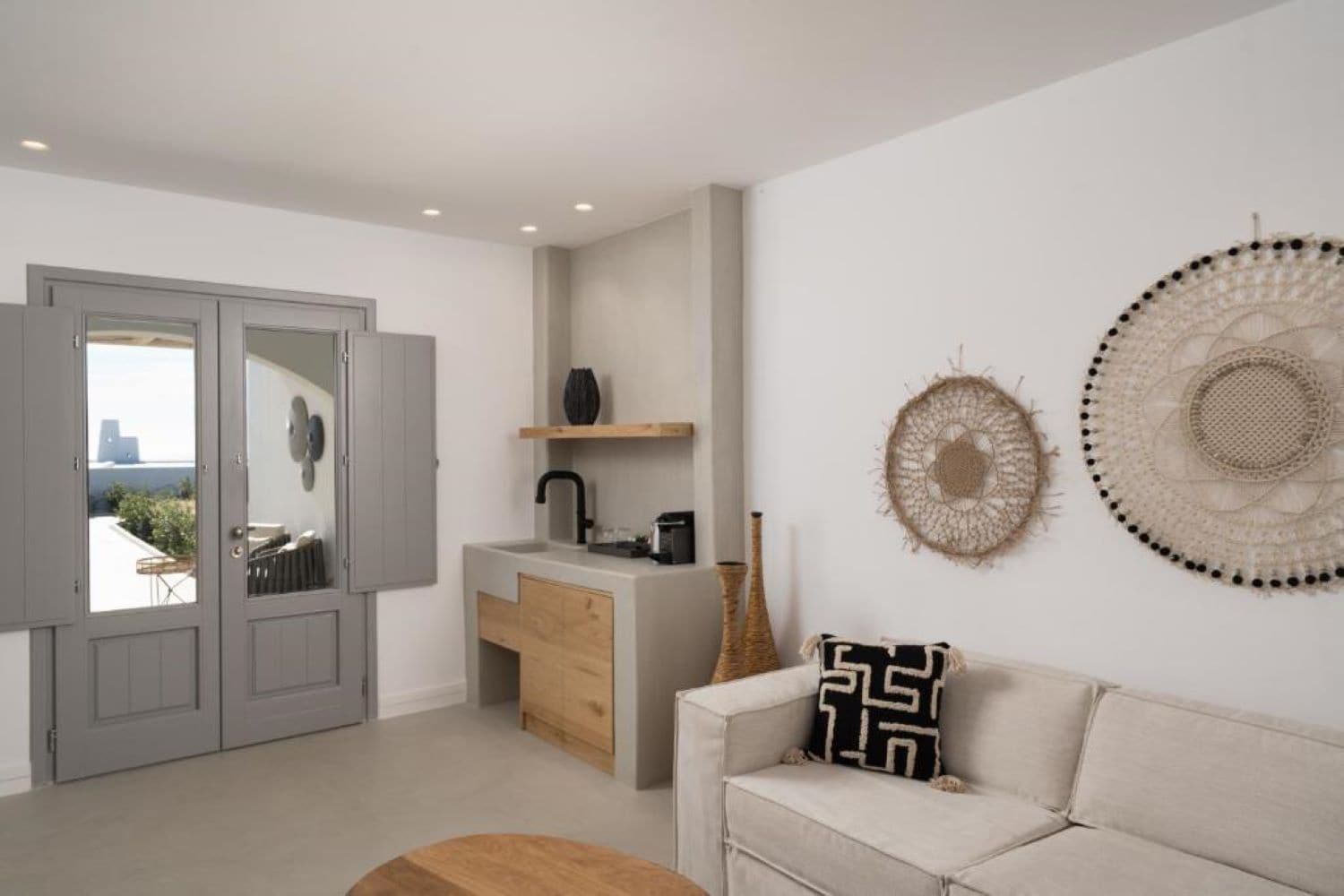 A modern living room with a sofa, a coffee table, a kitchen area with a sink and counter, and decorative wall art.