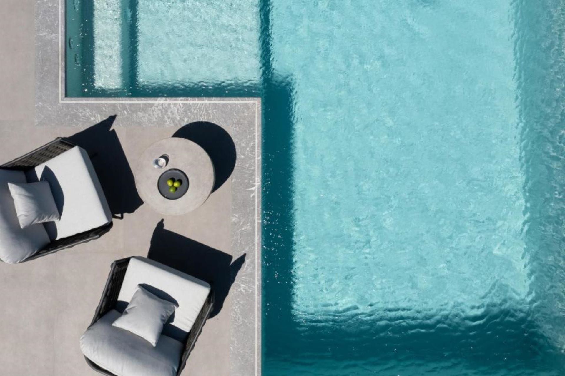 Vista aérea de una zona de piscina con sillas de descanso y un reloj de sol.