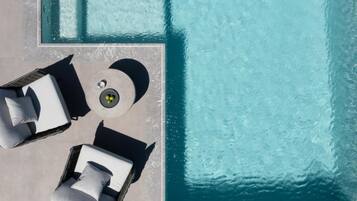 Vista aérea de una zona de piscina con sillas de descanso y un reloj de sol.