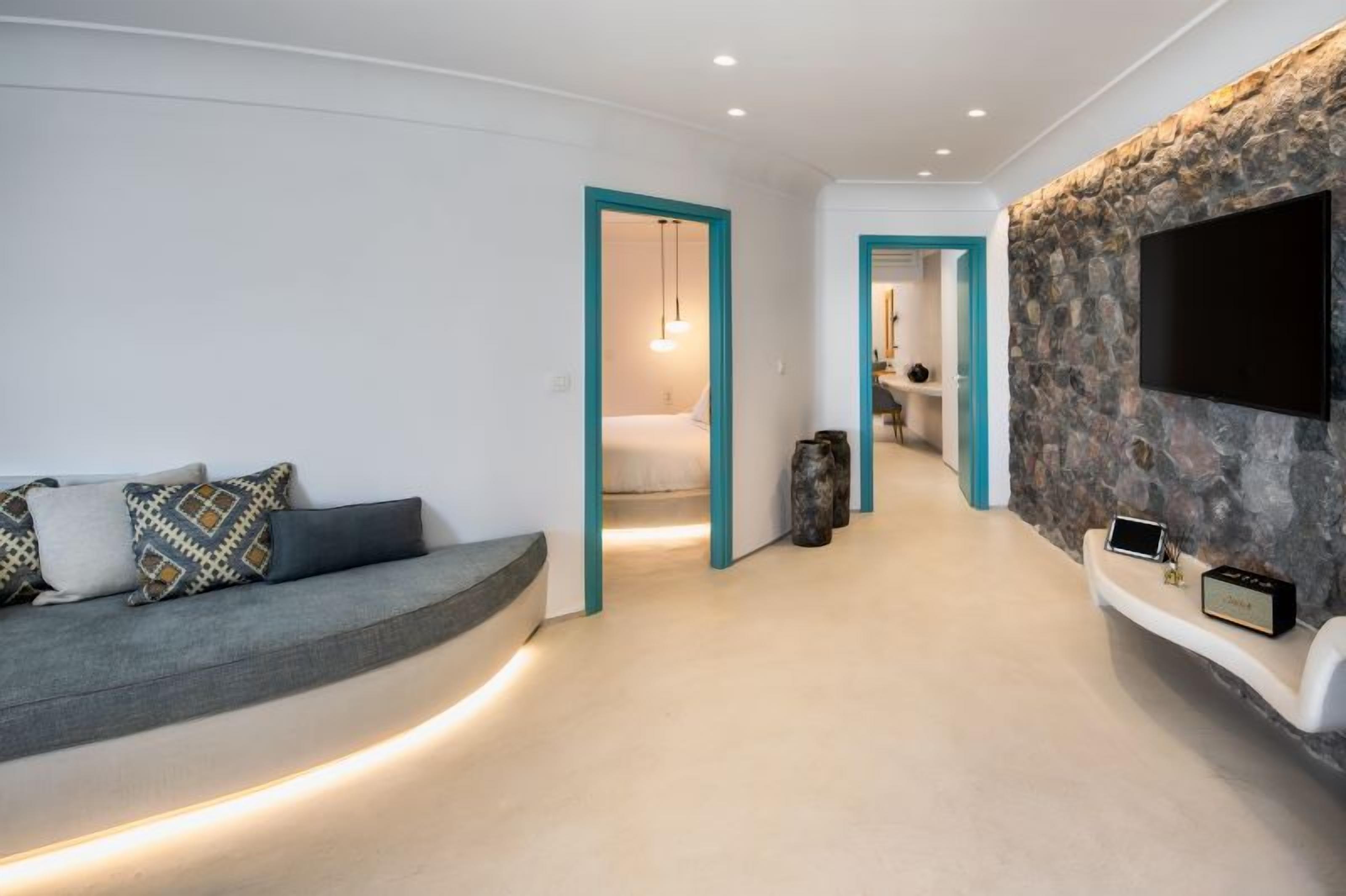 A modern interior with a sofa, a stone accent wall, a TV, and a hallway leading to another room.