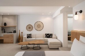 A modern living room with a sofa, coffee table, and decorative wall art. - La Ponta Villas&suites (Santorini)