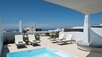 A rooftop pool area with lounge chairs and a clear view of the sea.