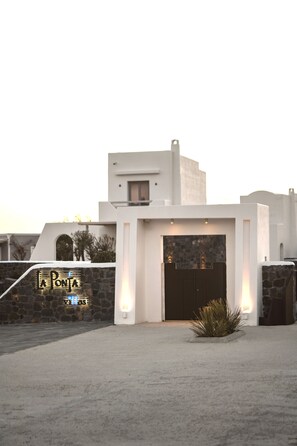 A modern building with a stone facade and a large dark entrance door. - La Ponta Villas&suites (Santorini)