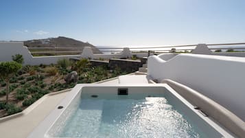 Una piscina en la azotea con vistas despejadas al mar y una colina distante.