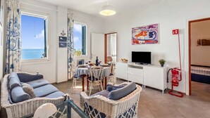 Une pièce meublée de meubles en osier, avec une table à manger, un téléviseur et un extincteur.