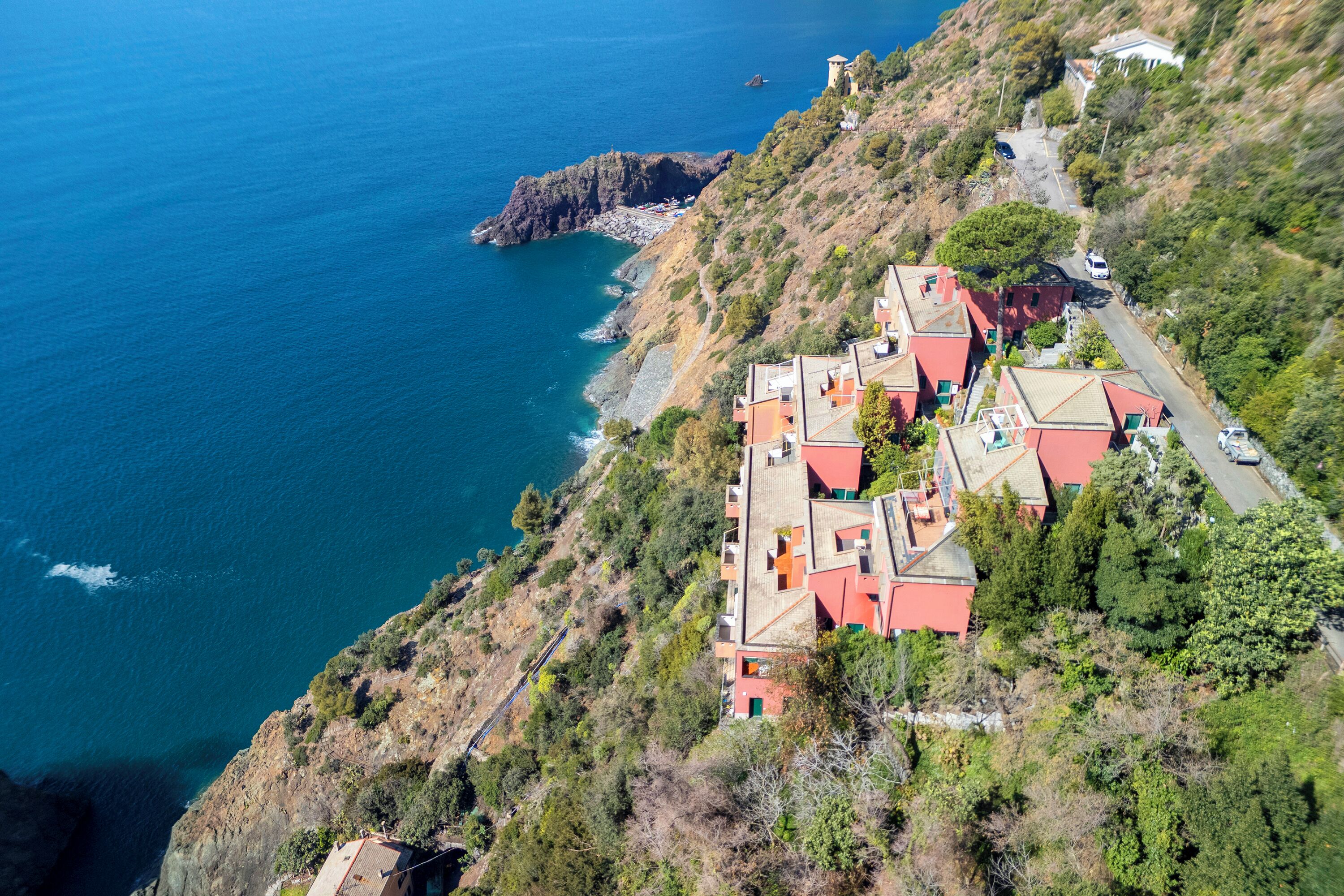 A coastal property with multiple buildings, a rocky coastline, and a clear view of the sea.