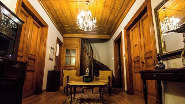 A wooden-floored hallway with a chandelier, a sofa, and a table. - Ottoman Suites By Sera House (Istanbul)