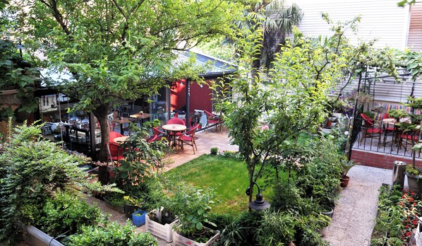 Une cour avec des sièges en plein air, un petit jardin et un bâtiment à la façade rouge.