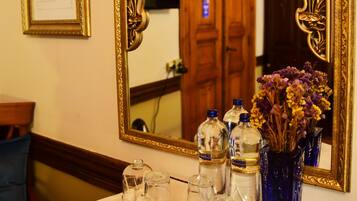 A table with a mirror, a framed certificate, and a vase with dried flowers.