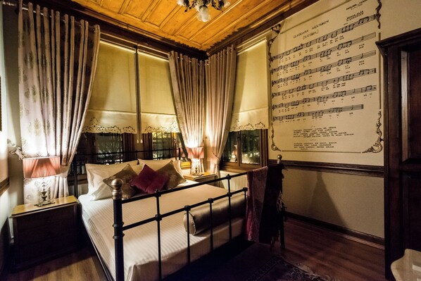 A room with a bed, curtains, a nightstand, a lamp, a window, and a wall with a musical score. - Ottoman Suites By Sera House (Istanbul)
