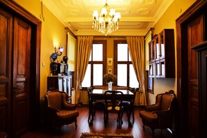 Comedor con candelabro, muebles de madera y ventanas amplias con cortinas.