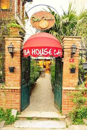 Una entrada de ladrillo con un toldo rojo que dice 'Sera House Cafe' y el número '31' en la pared.