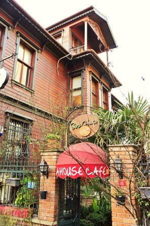 Un edificio de dos pisos con un letrero que dice 'House Cafe' y un toldo rojo.
