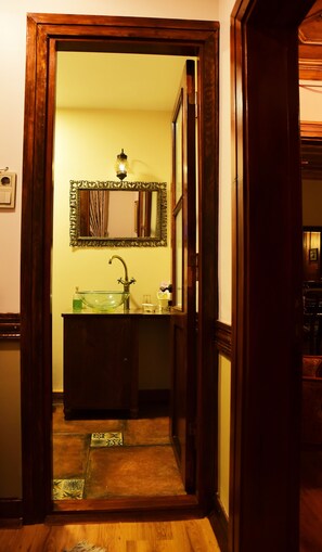 A bathroom with a wooden door, a mirror, a sink, and a light fixture. - Ottoman Suites By Sera House (Istanbul)