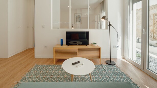 A modern living room with a television, a small table, a floor lamp, and a large window. - Apartment  by Interhome (Porto)