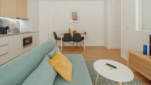 A modern living room with a sofa, a dining table with chairs, a kitchen area, and a small TV stand. - Apartment  by Interhome (Porto)
