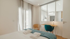 A hotel room with a bed, a desk, a chair, and a large mirror. - Apartment  by Interhome (Porto)