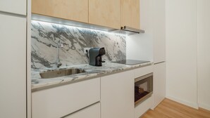 A modern kitchen with a marble countertop, a coffee machine, a built-in oven, and wooden cabinets. - Apartment  by Interhome (Porto)
