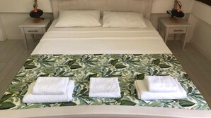Una habitación de hotel con una cama, dos mesitas de noche y una mesita de noche con una lámpara.