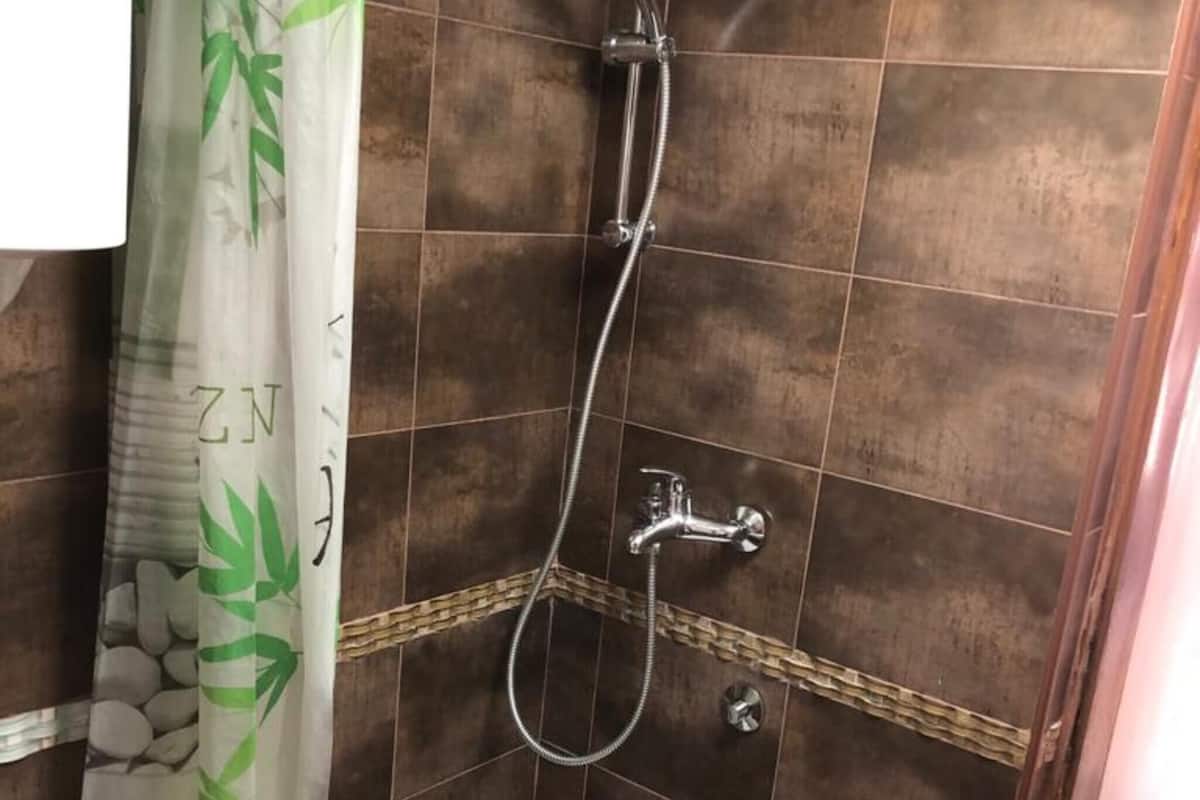 A shower area with a showerhead, handheld shower, and a wall-mounted faucet.