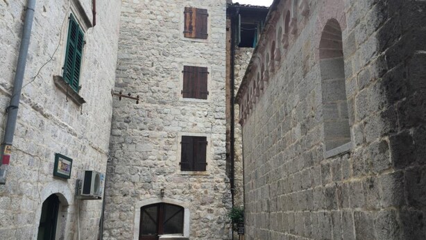 Un estrecho callejón de piedra con un edificio que presenta un arco central y varias ventanas.