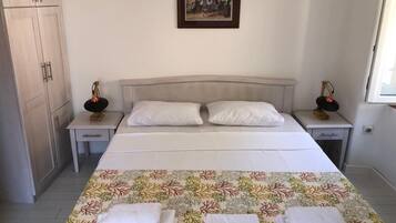 A bedroom with a bed, two nightstands, a wardrobe, a framed picture on the wall, and a window.