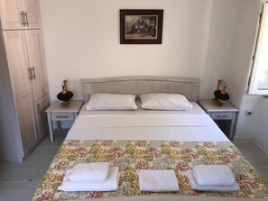 A bedroom with a bed, two nightstands, a wardrobe, a framed picture on the wall, and a window. - Athos Boutique Hotel (Kotor)