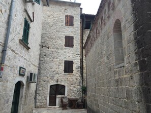 A narrow stone alleyway with a building featuring a central arched doorway and multiple windows. - Athos Boutique Hotel (Kotor)