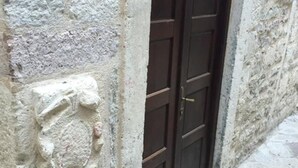 Un edificio de piedra con una puerta de madera oscura y un felpudo rojo pequeño en la entrada.