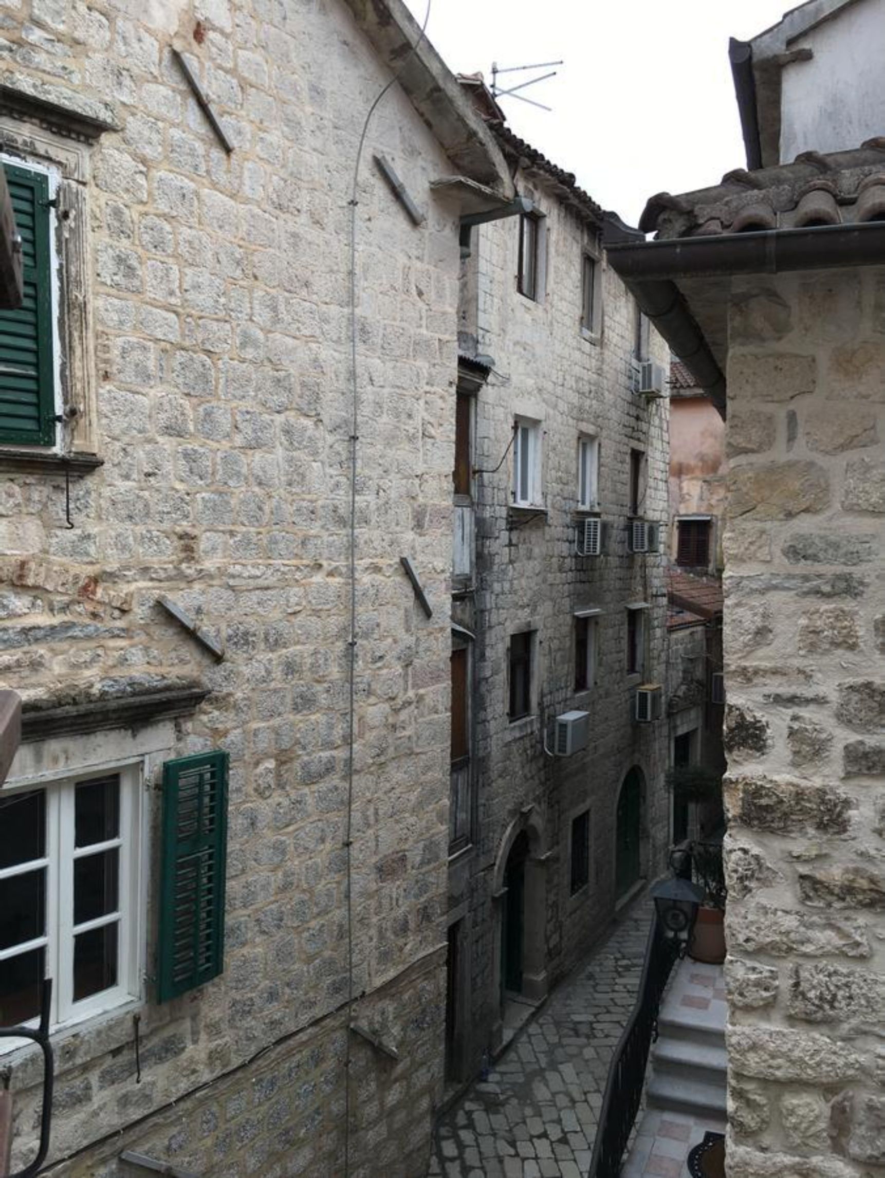 A narrow stone alleyway between buildings with arched doorways and a small staircase.