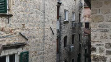 A narrow stone alleyway between buildings with arched doorways and a small staircase.