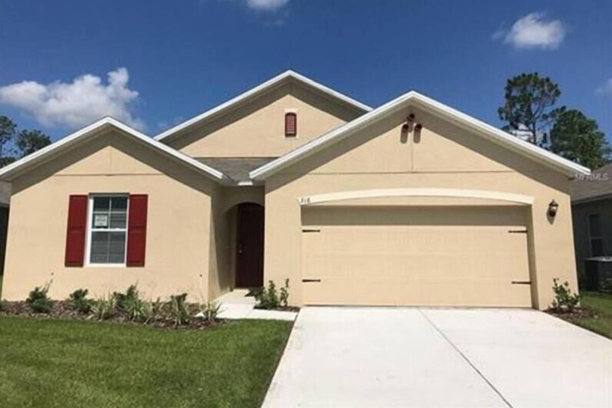 A single-story house with a beige exterior, a red door, and a garage.