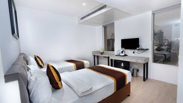 A hotel room with two beds, a desk, a television, and a city view.