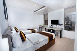 Habitación de hotel con dos camas, un escritorio, un televisor y vista a la ciudad.
