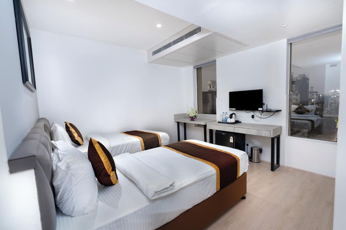 Een hotelkamer met twee bedden, een bureau, een televisie en uitzicht over de stad.