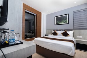 Una habitación de hotel moderna con una cama, un televisor, una cafetera y una botella de agua sobre una bandeja.