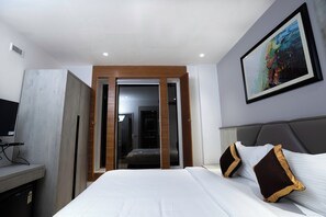 Een moderne hotelkamer met een bed, een televisie, een schilderij en een kledingkast.
