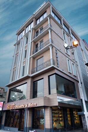 Ein mehrgeschossiges Gebäude mit Bäckerei und Bistro im Erdgeschoss, das große Fenster und ein modernes Design aufweist.