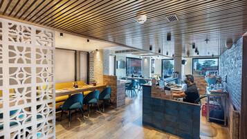 A restaurant interior with wooden ceiling, blue chairs, and a counter.