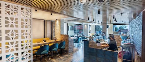 A restaurant interior with wooden ceiling, blue chairs, and a counter.