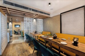 Un comedor moderno con una larga mesa de madera, varias sillas y una pantalla de televisión.