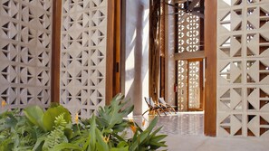 A traditional Japanese-style entrance with wooden lattice doors, a wooden floor, and a view of a room with a ceiling fan. - Amainah Bacalar (Bacalar)