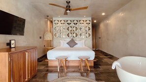 A modern bedroom with a bed, two stools, a vanity, a ceiling fan, and a large bathtub. - Amainah Bacalar (Bacalar)
