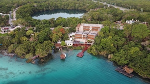 An aerial view of a coastal resort with a large building, a dock, and clear turquoise waters.