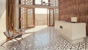 A reception area with a check-in counter, a patterned floor, and a large wooden door. - Amainah Bacalar (Bacalar)