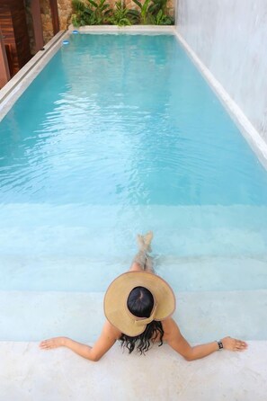 A person lying on a poolside with a clear view of the pool.